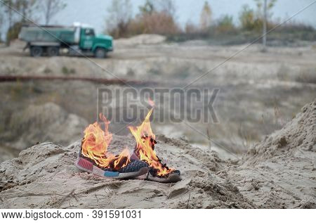 Burning Sports Sneakers Or Gym Shoes On Fire Stand On Sandy Beach Coast. Athlete Burned Out. Physica