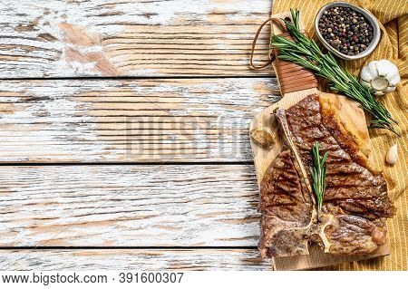 Grilled T Bone Steak On A Chopping Board. Cooked Tbone Beef. White Wooden Background. Top View. Copy