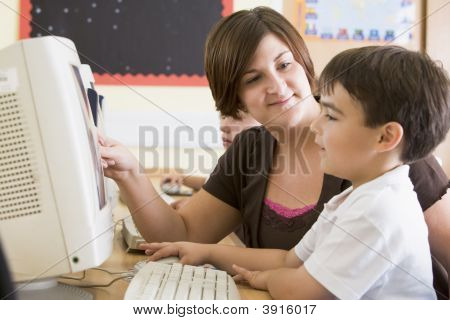 Insegnante di aiutare i bambini a studiare in aula computer