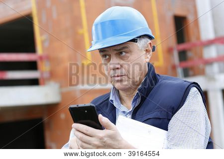 Empresario en obra con smartphone