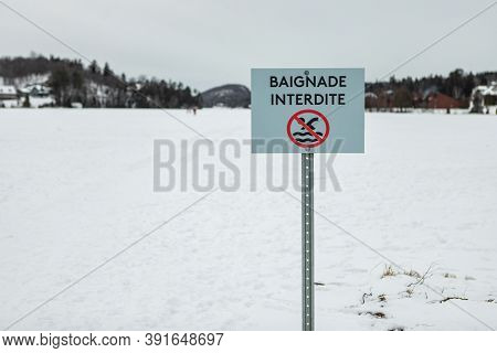 Signboard Of Baignade Interdite Written In French Meaning No Swimming With Illustrator On Ice Layer 
