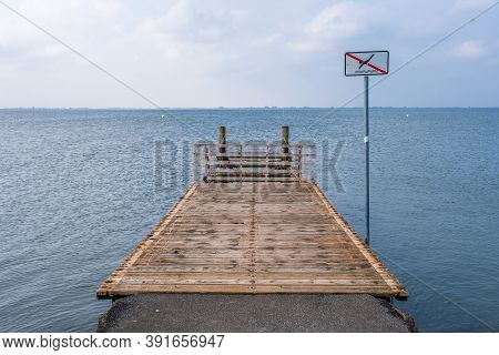 A Wooden Pier On The North Sea Coast With A Sign Bathing Is Prohibited
