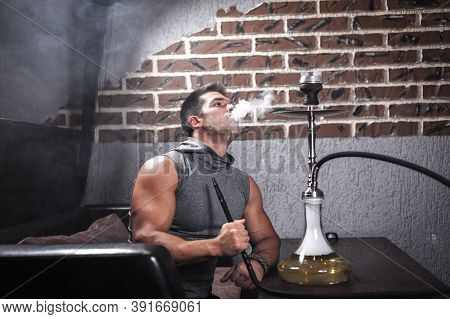 Sexy Man Relaxes In A Hookah In Night Club.