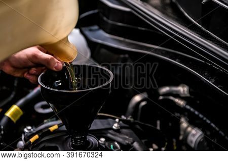Close-up Of Mechanic Adding Oil With A Funnel