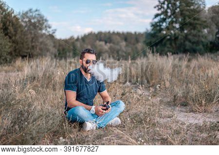 Modern Vape Man Blowing A Lot Of Smoke Using Vape E-cigarette. Non-tobacco Smoking.