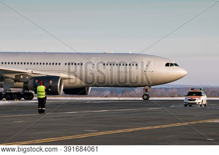 Passenger Airplane Is Moving Behind The Follow Me Car. Airport Ground Crew Meets Aircraft