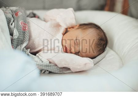 Close Up Photo Of A Sleeping Newborn Baby In Warm Clothes Covered With A Quilt In Her Bed