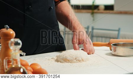 Baker Adding Flour On The Pile By Hand Preparing Bread Dough. Close Up Of Retired Elderly Chef With 