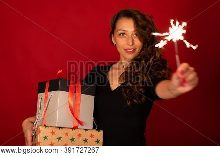 Pretty Woman With Holiday Gift And Burning Sparkler On Red Background, Focus On Female Shopper, Copy