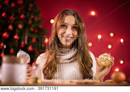 Portrait Of Pretty Smiling Brunette Girl Decorating Freshly Baked Christmas Cookies On Blurred Backg