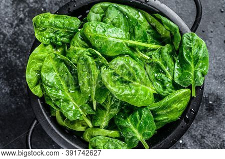 Young Raw Spinach In A Colander. Black Background. Top View