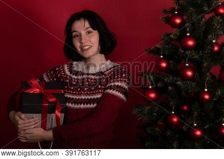 Smiling Brunette Girl Dressed In Knitted Winter Pattern Sweater Embraced Gift Box With Christmas Pre