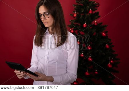 Thoughtful Brunette With Long Hair In Glasses Calculates New Year And Christmas Expenses On Calculat