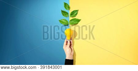 Person Holding A Light Bulbs With Green Leaves