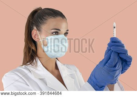 Attractive Female Doctor Wearing A Virus Protection Mask And Latex Gloves Carrying A Vaccine Syringe