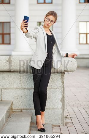 Full length portrait of a young beautiful girl in a gray jacket and black jeans