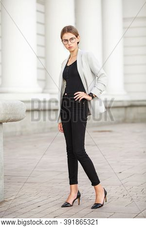 Full length portrait of a young beautiful girl in a gray jacket and black jeans