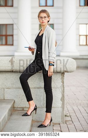 Full length portrait of a young beautiful girl in a gray jacket and black jeans