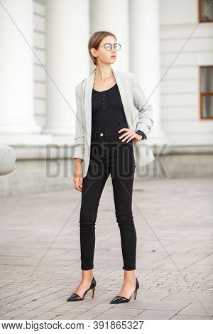 Full length portrait of a young beautiful girl in a gray jacket and black jeans