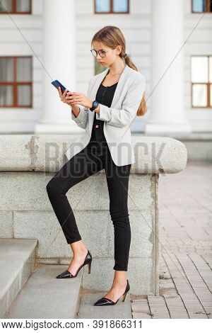 Full length portrait of a young beautiful girl in a gray jacket and black jeans