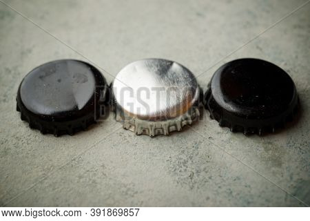 Three bottle caps on a stone table.