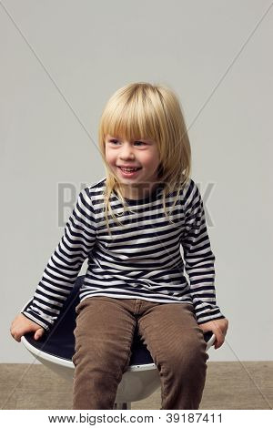 สาวบลอนด์ 3 ปีในกางเกงยีนส์อยู่บนเก้าอี้สูง