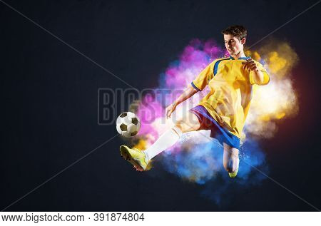 Soccer Player Kicking Ball In Colorful Smoke. Sportsman In Yellow And Blue Uniform In Action. Soccer