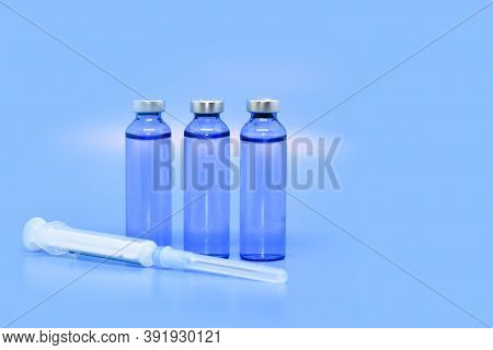 Transparent Medical Ampoules And A Syringe On A Light Blue Background. Concept: Medicine, Injections