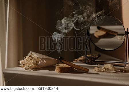 Palo Santo With Jet Of Smoke, Mirror And Dried Flowers On A Neutral Background. Abstract Picture. Mi