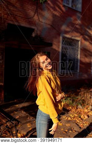 Beautiful Caucasian Young Woman Walking And Having Fun Outdoors In Autumn Time. Bright Yeallow Color