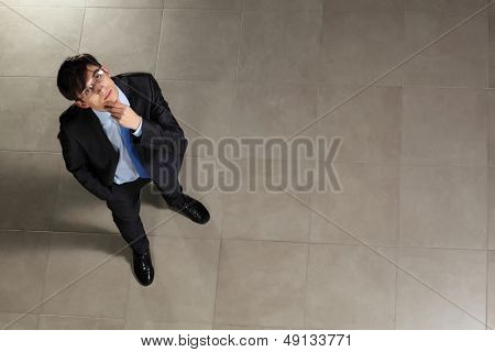 Image of young businessman in glasses looking thoughtfully. Top view
