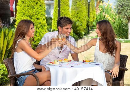 Three Friends Toasting While Having Lunch Outdoors