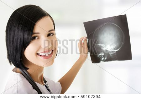 Pretty caucasian female doctor looking at x-ray. 