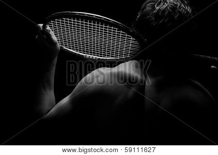 Tennis player and his racket highlighted on black background
