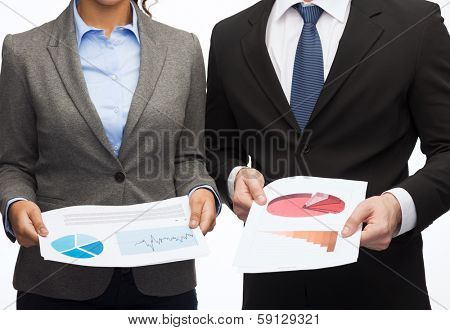 business and economy concept - smiling businesswoman and businessman with graphs and charts