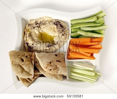 Top view of a dip tray with hummus, bread, carrot sticks, celery and cucumber.