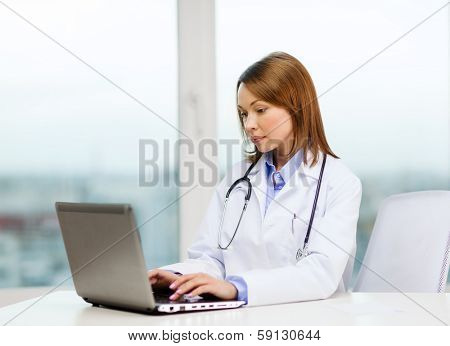 medicine and healthcare concept - busy doctor with laptop computer