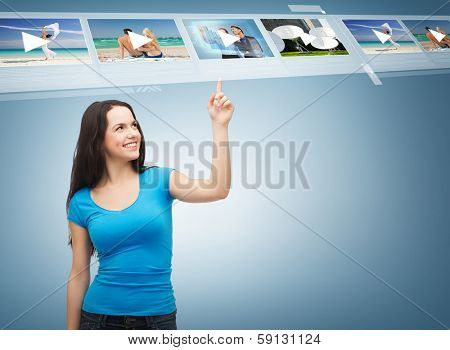 advertisement concept - attractive teenager in casual clothes pointing her finger at videos
