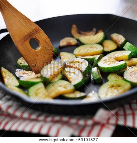 stirring fried zucchini in an iron skillet