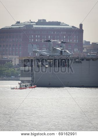 NEW YORK - MAY 27: A US Coast Guard boat runs alongside the stern of the USS Oak Hill (LSD 051) on the Hudson River after departing Pier 92 at the end of Fleet Week NY on May 27, 2014.