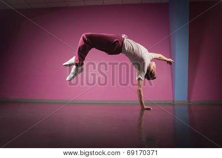 Cool break dancer doing handstand on one hand in the dance studio
