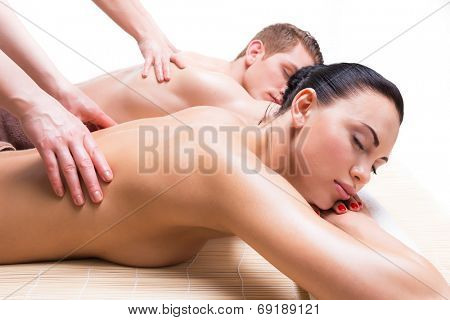 Beautiful couple lying  in a spa salon enjoying a deep tissue back massage together.