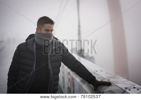 Young man in winter fashion standing outdoors with scarf hiding his face