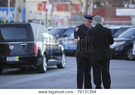 NYPD officers with hearse in background