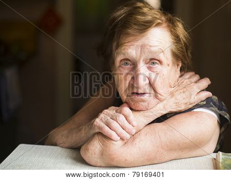 Poor old woman in her home, looking into the camera.