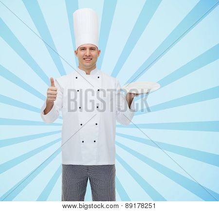 cooking, profession, advertisement and people concept - happy male chef cook holding something on empty plate and showing thumbs up over blue burst rays background