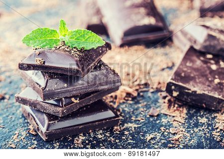 Chocolate. Black chocolate. A few cubes of black chocolate with mint leaves.