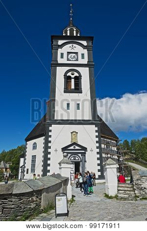 Tourists walk in front of the Roros church and bell tower in Roros, Norway.