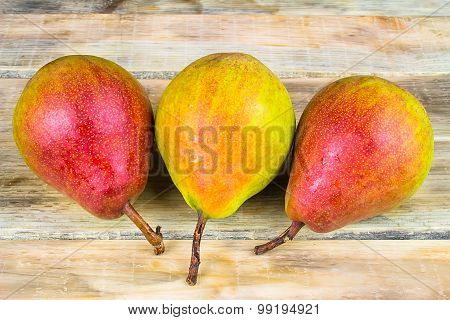 Three Ripe Yellow And Red Pears On Rustic Wooden Background