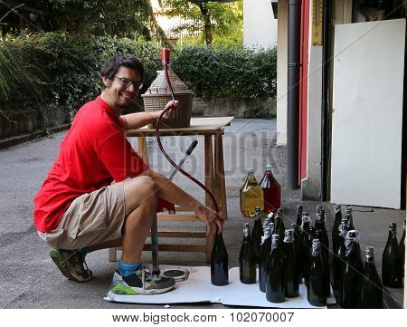 Young Man Smiling While Bottling The Wine At Home